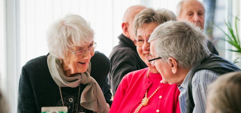 Tre äldre personer i livligt samspråk vid ett bord