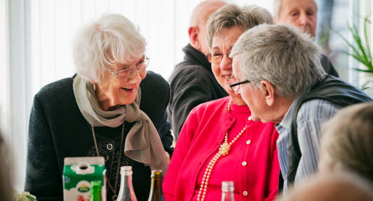 Tre äldre personer i livligt samspråk vid ett bord