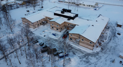 Drönarbild på  skolbyggnad med snö runtomkring.