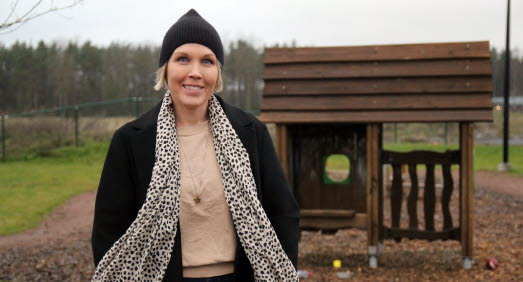 Linda Persson står utomhus på en förskolegård och tittar leende in i kameran