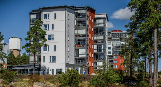 Flera lägenhetshus, med gråa och orangeröda väggar och inglasade balkonger. I bakgrunden skymtar ett vattentorn. 