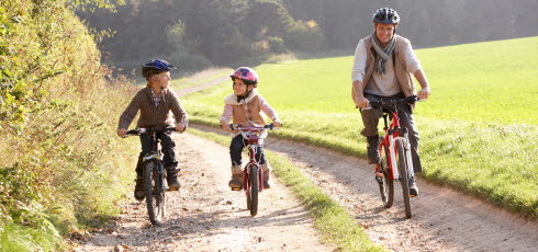 Barn och vuxen cyklar på grusväg 