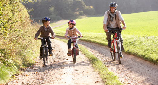 Barn och vuxen cyklar på grusväg 