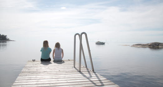 Två tjejer som sitter och blickar ut över Vänerns horisont. 